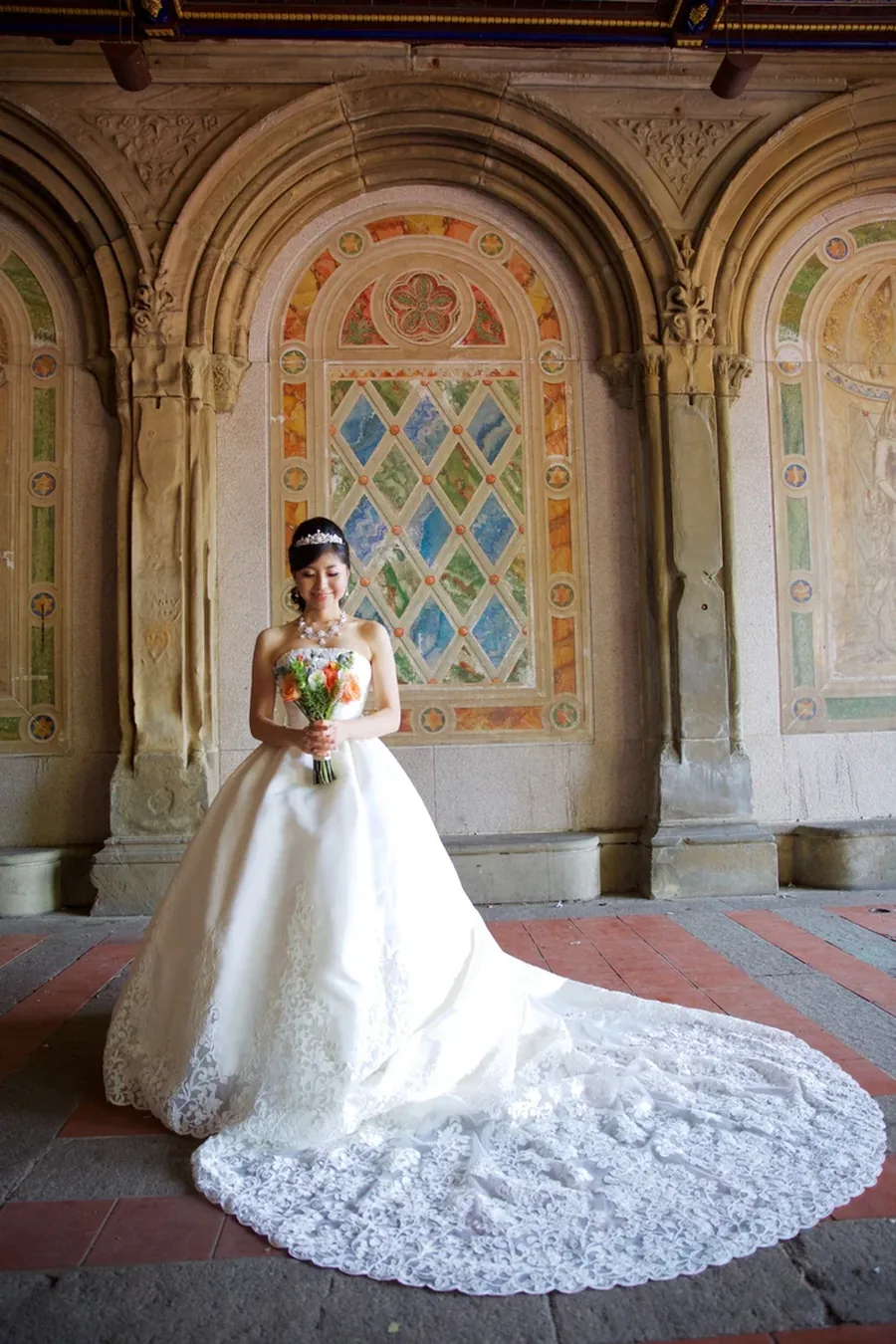 A bride with her train spread out beneath the arches of Bethesda Terrace