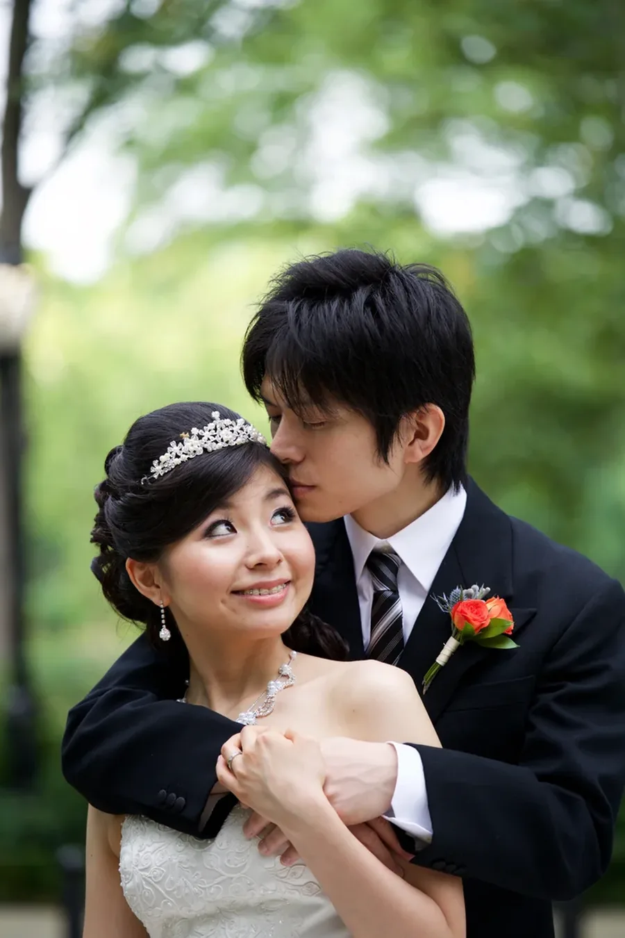 A groom kissing his bride's forehead in a Central Park garden