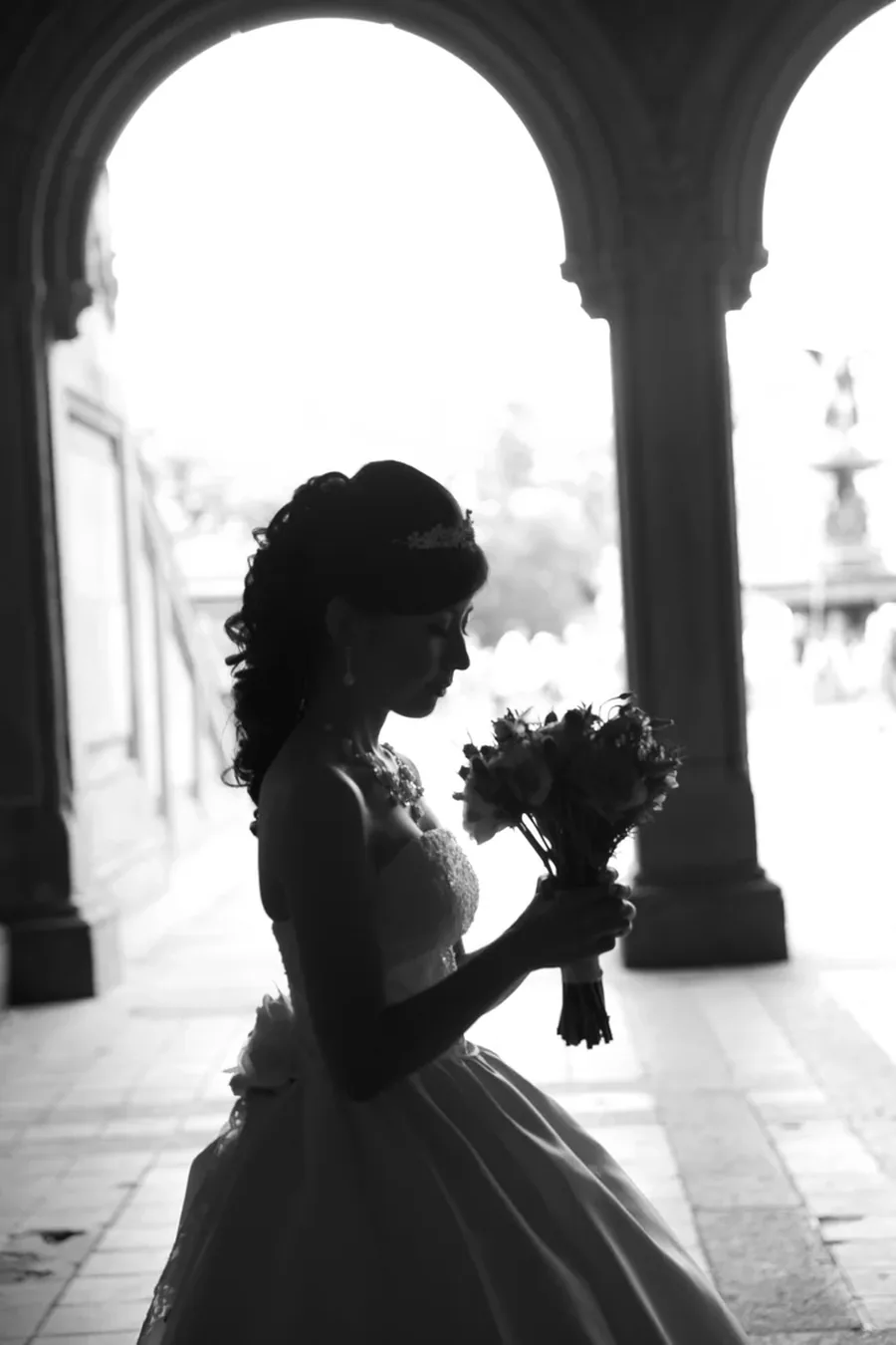 A bride photographed in silhouette against the arches of Bethesda Terrace