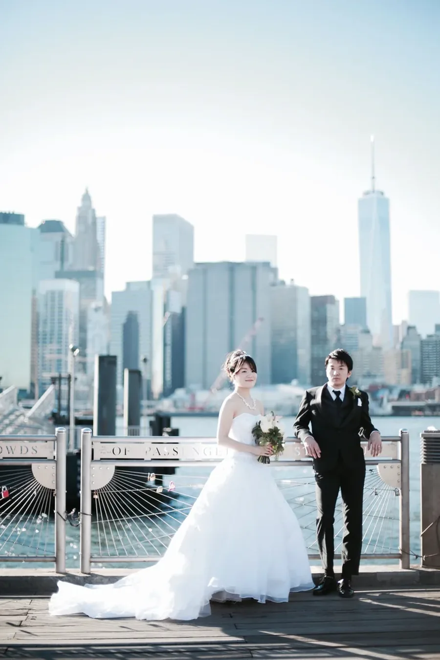 A couple on the Brooklyn pier with the Manhattan skyline behind them