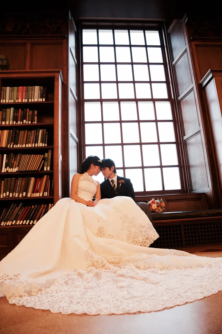 A couple in a wood panelled library beside a tall window