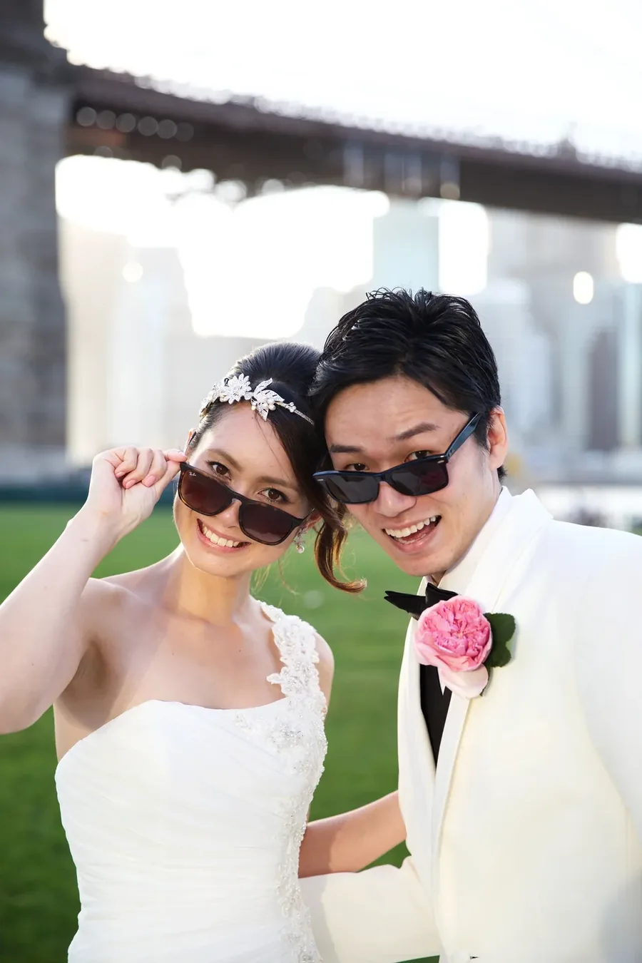 A couple lowering their sunglasses and grinning at the camera
