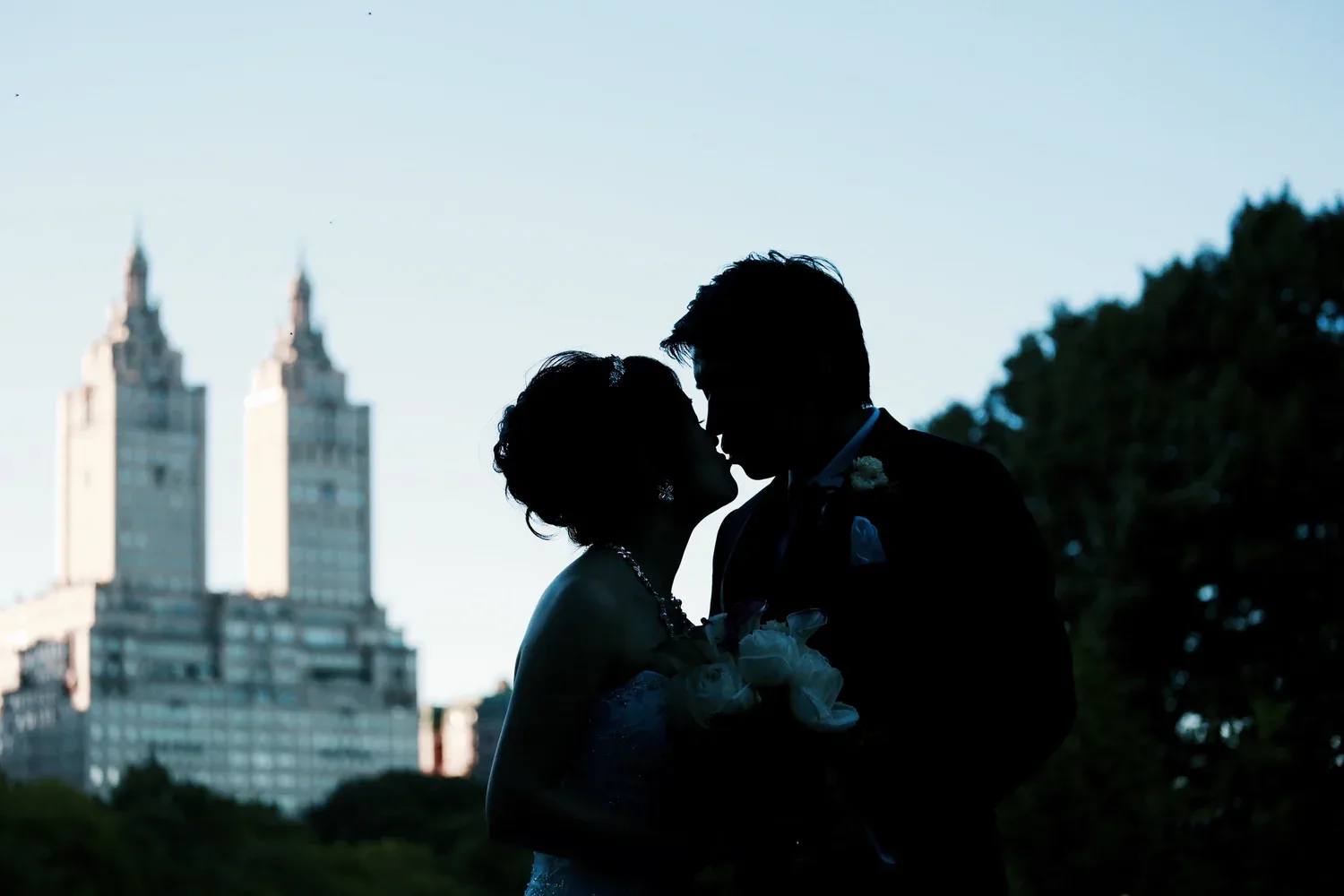 A couple kissing in silhouette against the towers of the Upper West Side at dusk
