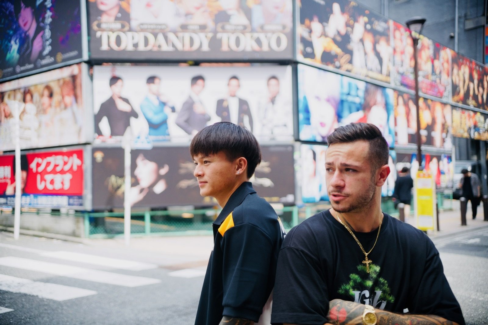Two travelers photographed on a street in Kabukicho