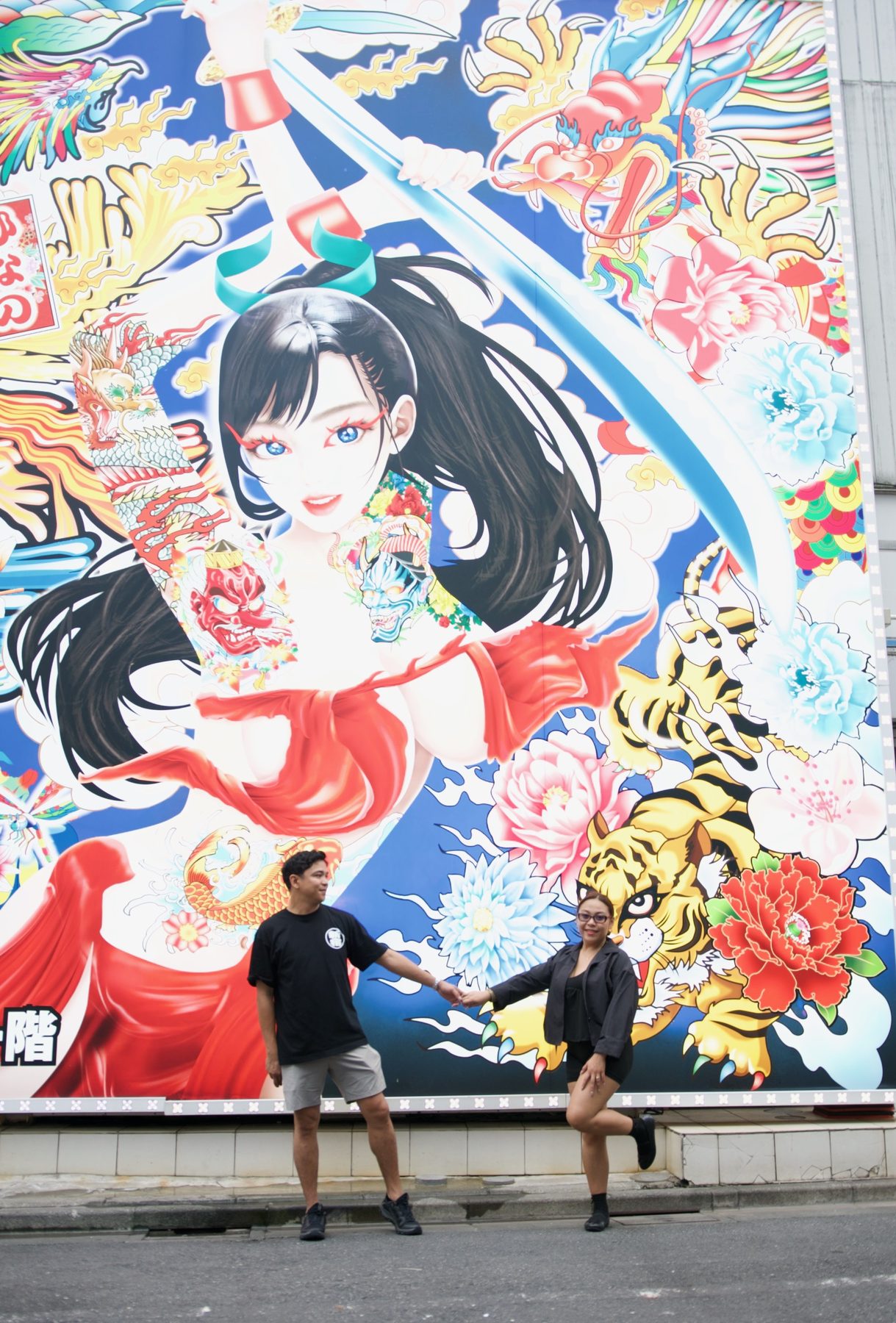 A couple reaching for each other's hands in front of a large painted mural