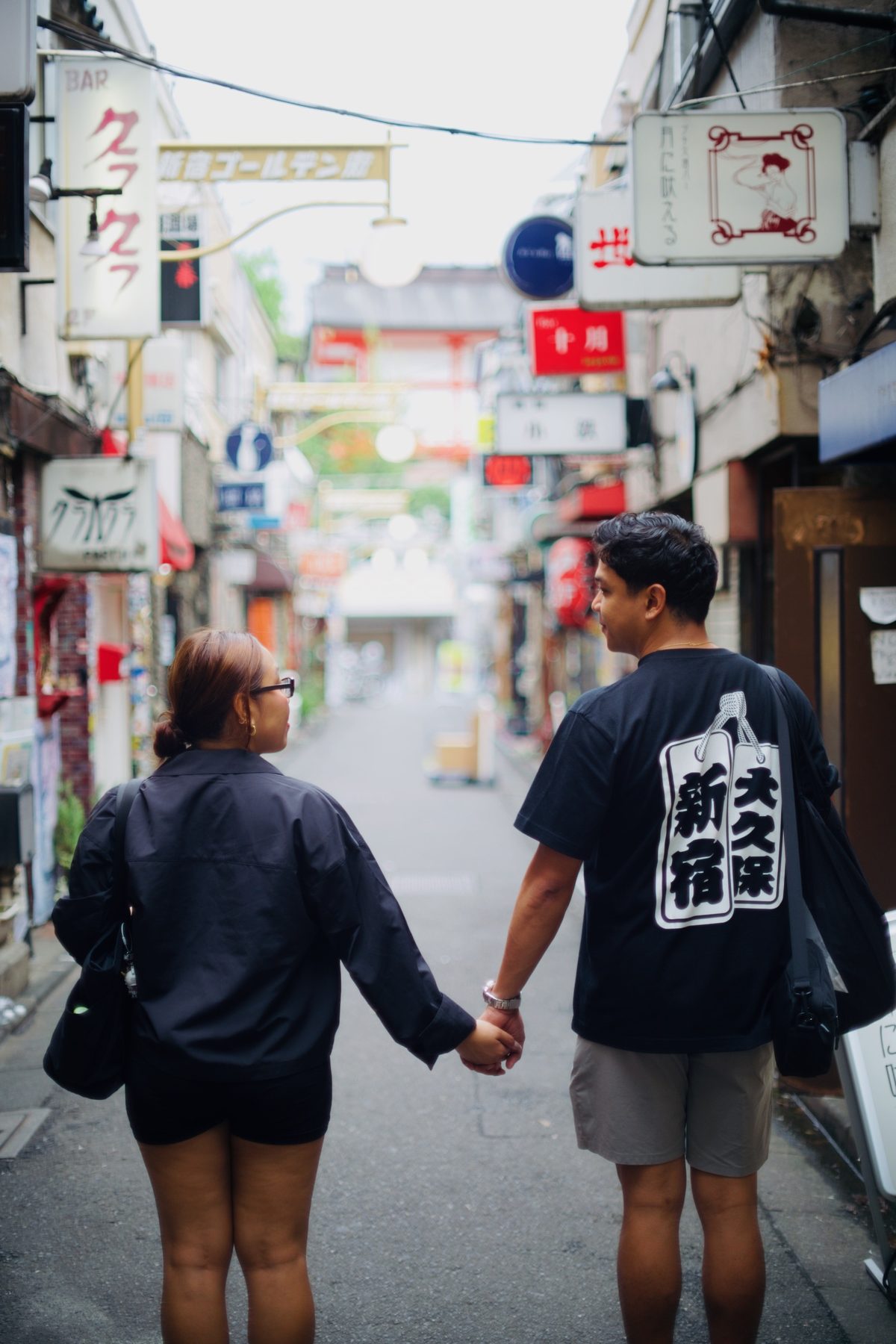 A couple holding hands, walking away down a narrow lane